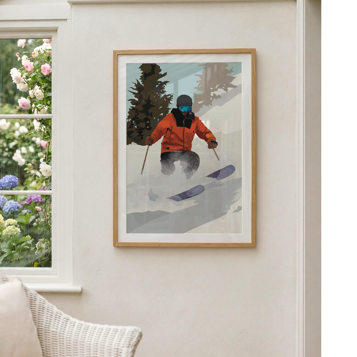 A framed art print depicting a skier in an orange jacket on a snowy mountain, displayed on a light beige wall next to a window with flowers.