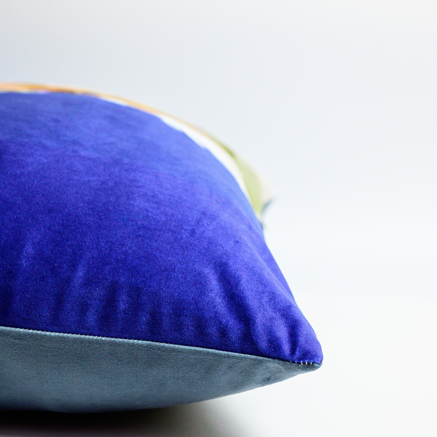 A blue velvet cushion featuring an illustration of a hare with black tipped ears Side view