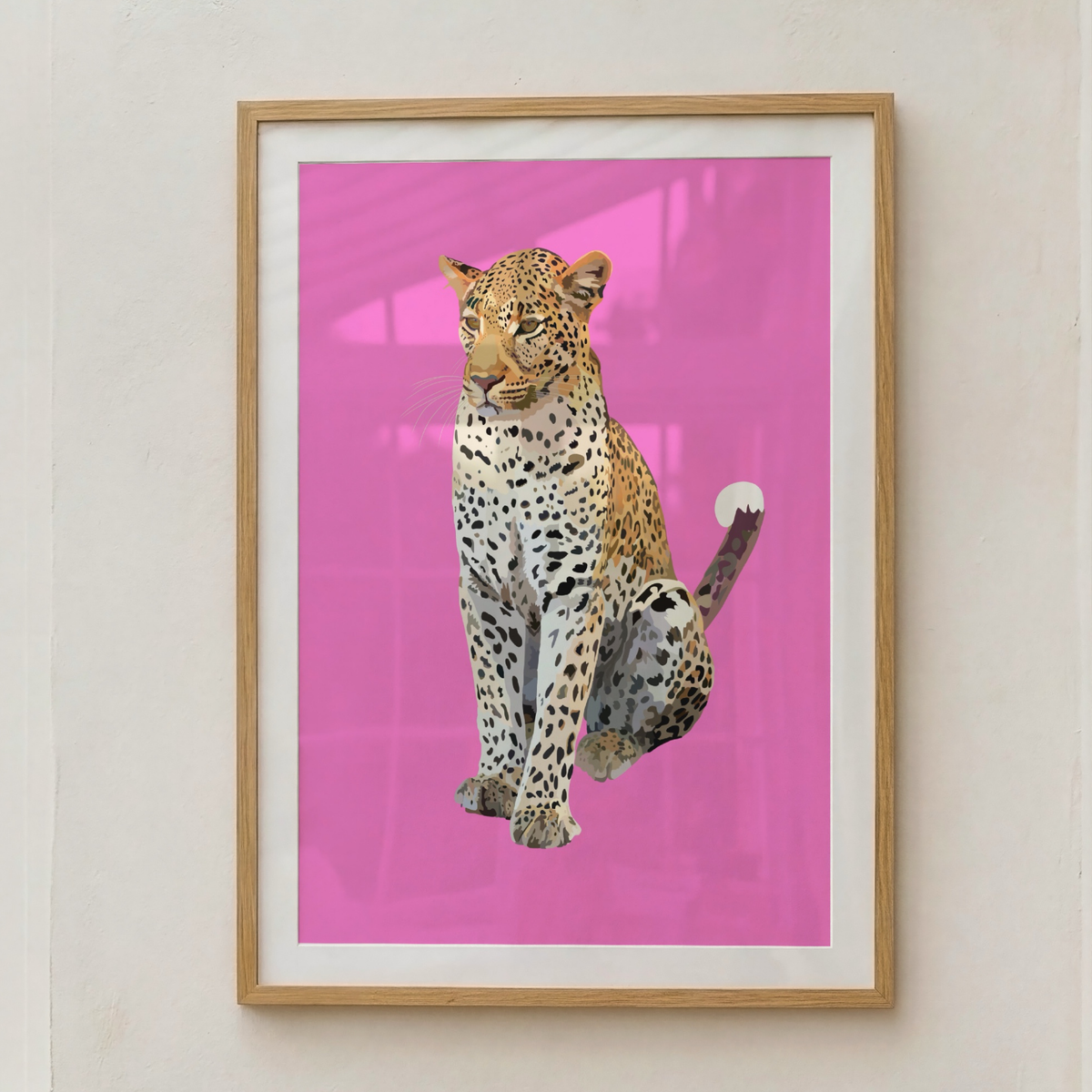 A framed art print featuring a realistic leopard sitting against a vibrant pink background, mounted on a light beige wall.