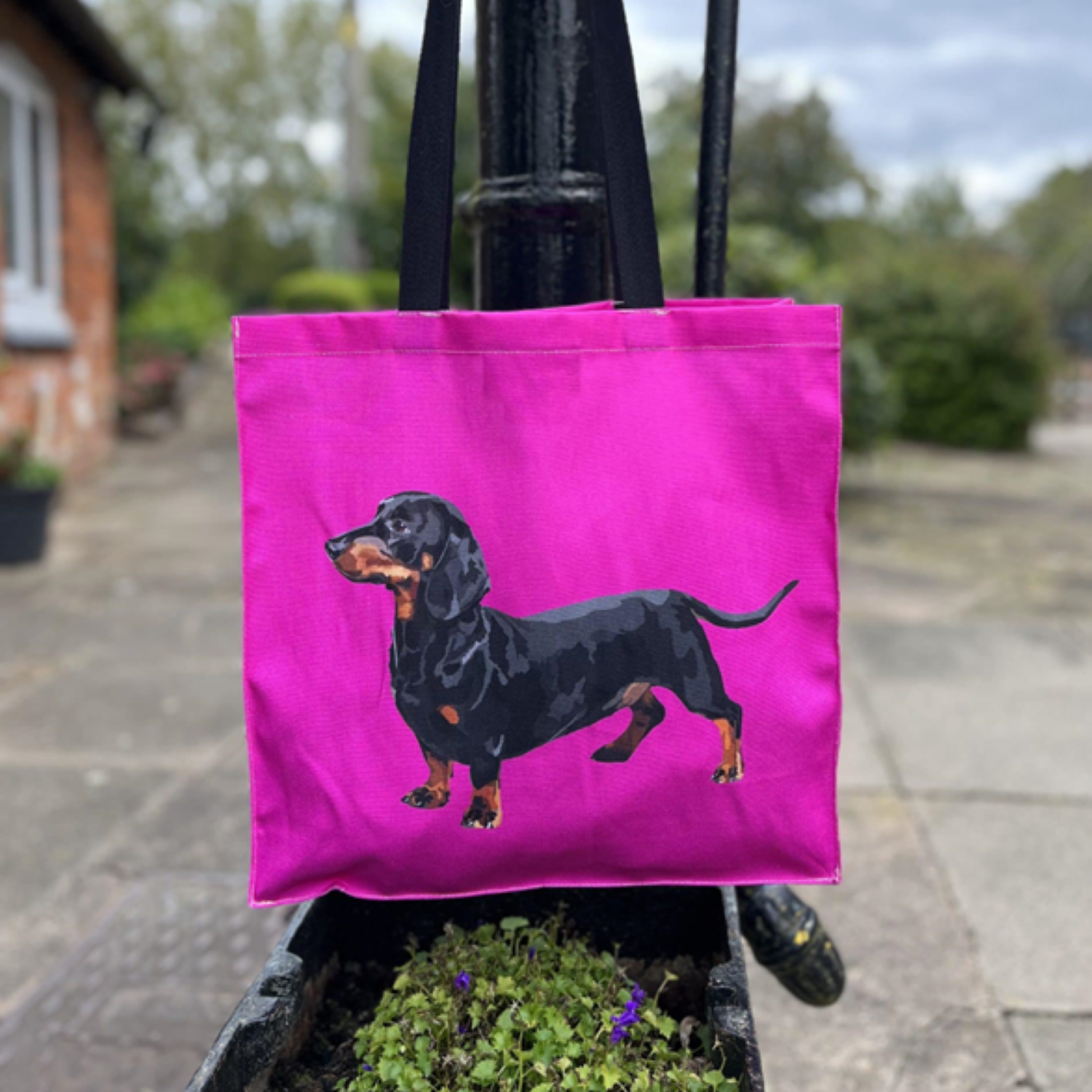 A bright pink sausage dog tote bag hanging from an old fashioned pump
