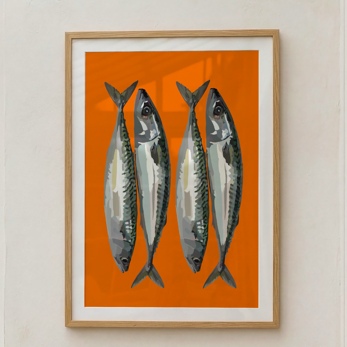 Framed wall art featuring four illustrated mackerel on a bright orange background, mounted in a light wood frame with a white mat against a beige wall.