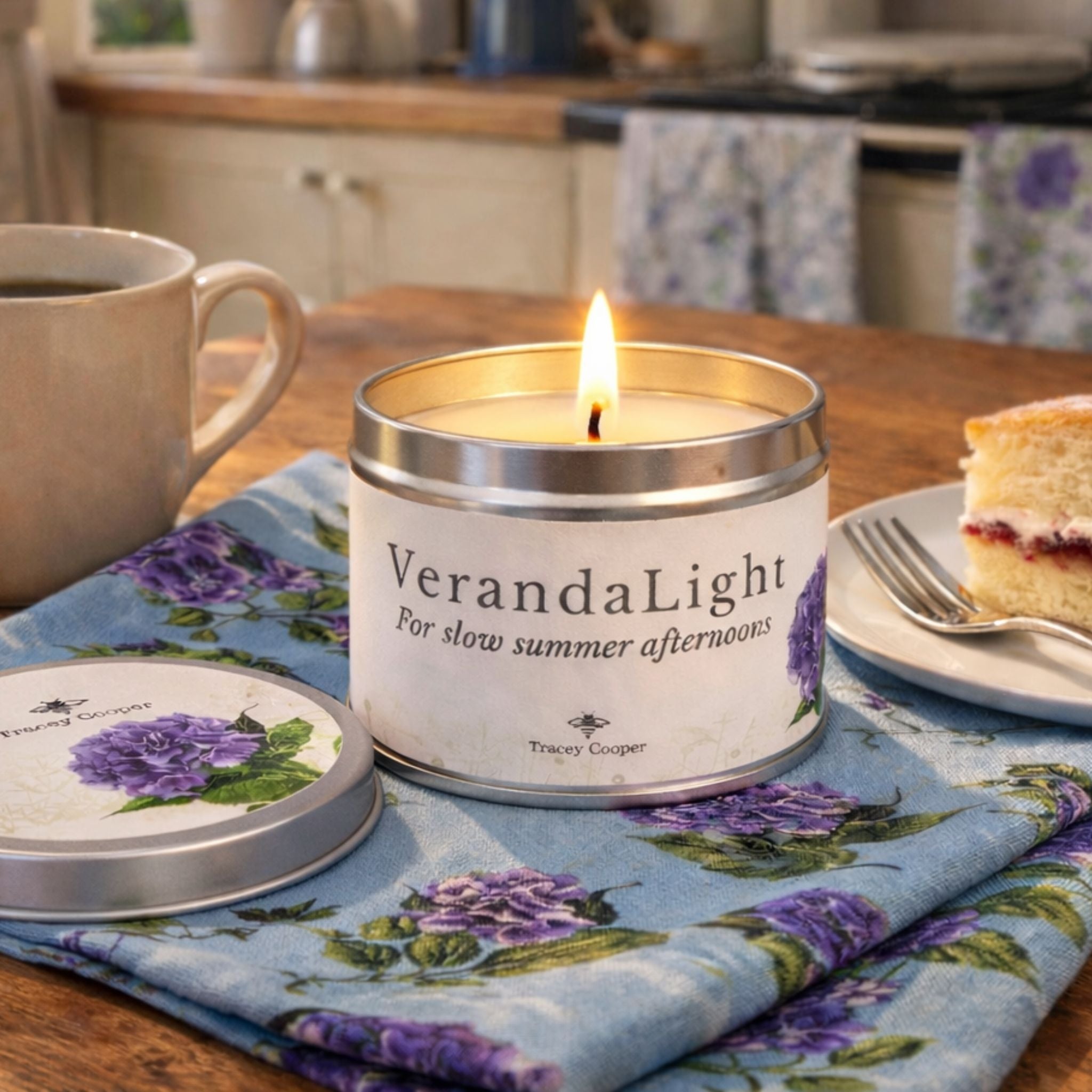 VerandaLight scented candle on hydrangea tea towel in a British country kitchen with coffee and Victoria sponge cake