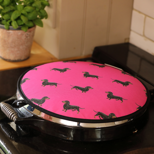 Hand-illustrated sausage dog hob cover in pink designed for Aga cookers